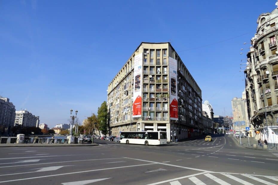 Eckgebäude mit Werbeplakaten in einer städtischen Umgebung unter blauem Himmel.