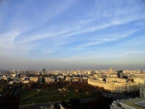 Blick auf eine Stadtlandschaft mit Wolken und mehreren Gebäuden im Vordergrund.