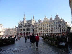 Historische Gebäude und Menschen auf einem Platz in Brüssel mit klarem Himmel.