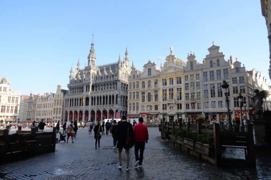 Historische Gebäude und Menschen auf einem Platz in Brüssel mit klarem Himmel.
