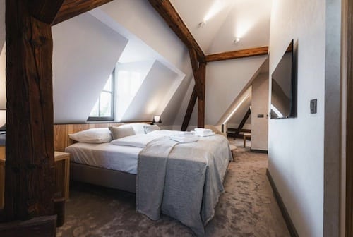 Hotelzimmer mit Doppelbett, Holzdeckenbalken und modernem Design.