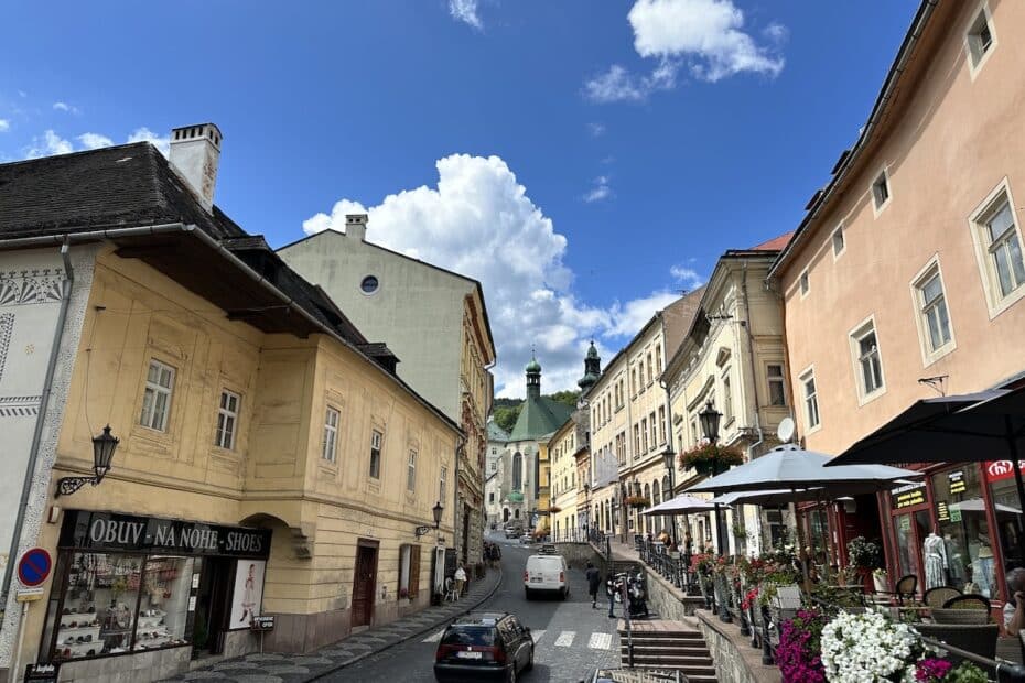Blick auf eine gepflasterte Straße mit historischen Gebäuden und Wolken im Hintergrund.