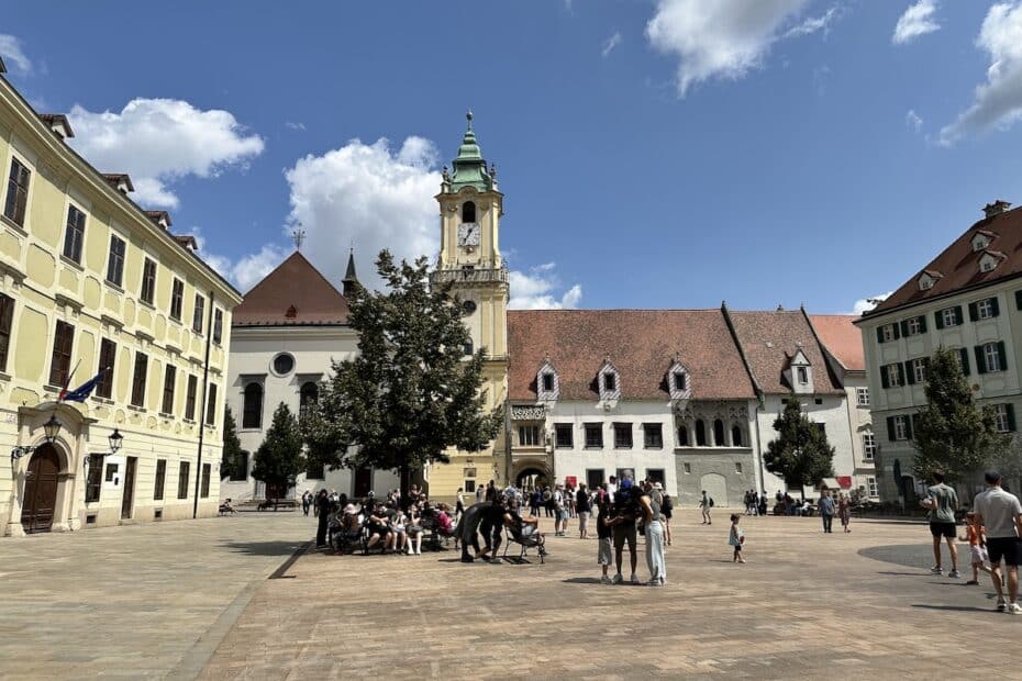 Ein Platz mit historischen Gebäuden, einer Kirche und Menschen, die sich versammeln und entspannen.