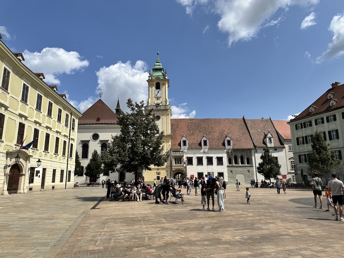 Ein Platz mit historischen Gebäuden, einer Kirche und Menschen, die sich versammeln und entspannen.
