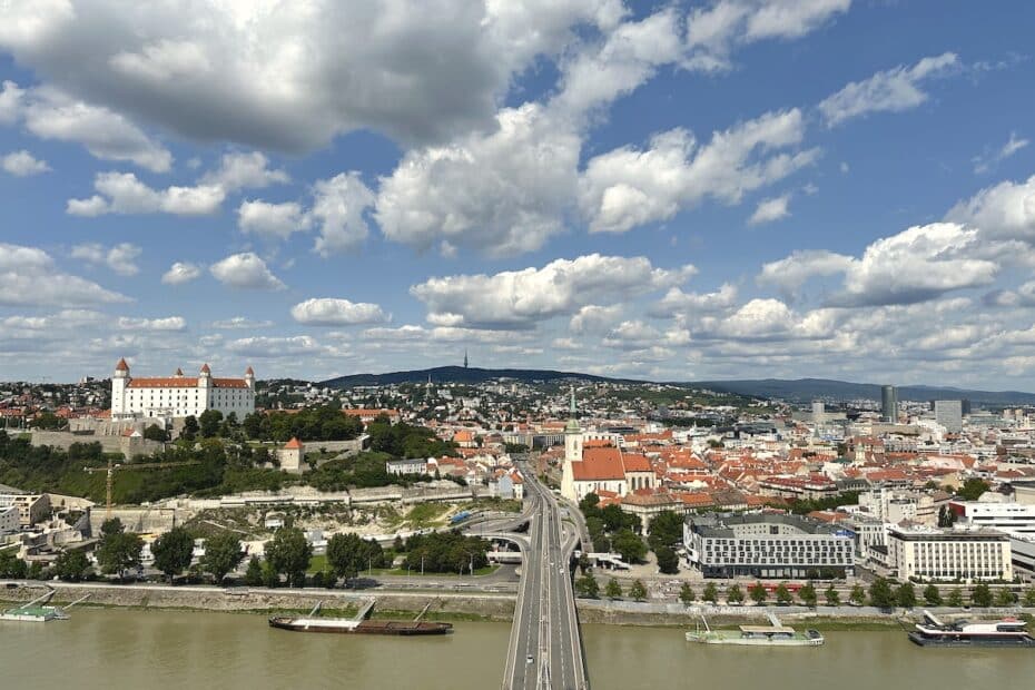 Panoramablick auf Bratislava mit der Burg und der Donau unter einem bewölkten Himmel.