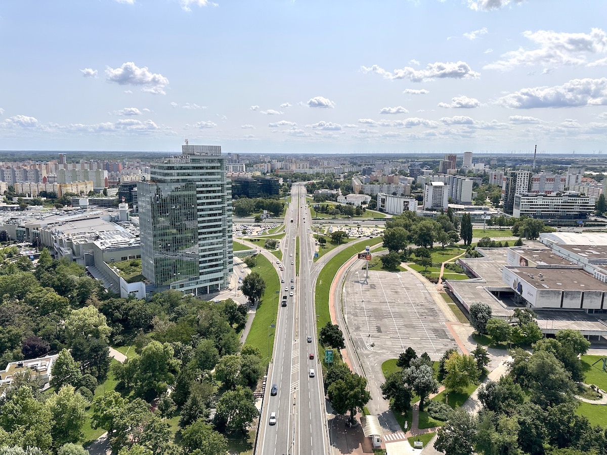 Luftaufnahme einer Stadt mit einer Hauptstraße und modernen Gebäuden auf beiden Seiten.