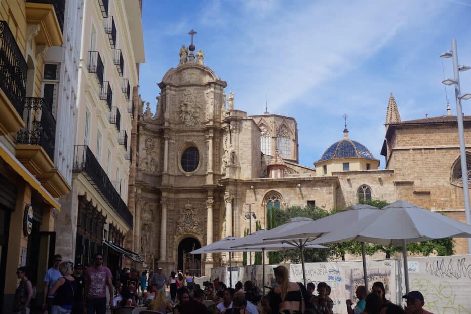 Historische Kirche mit barocker Fassade und umliegenden Menschen in einem Stadtbereich von Valencia.