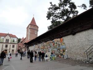 Eine Wand mit verschiedenen Kunstwerken, die an einer Stadtmauer aus Stein ausgestellt sind.