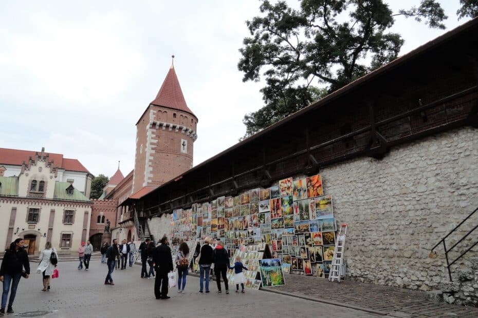 Eine Wand mit verschiedenen Kunstwerken, die an einer Stadtmauer aus Stein ausgestellt sind.