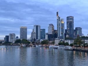 Skyline von Frankfurt am Main mit modernen Wolkenkratzern und Booten am Fluss.