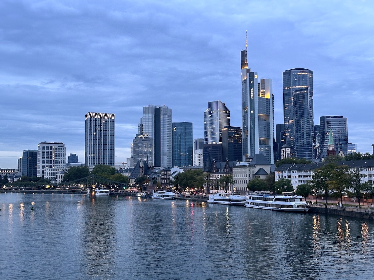Skyline von Frankfurt am Main mit modernen Wolkenkratzern und Booten am Fluss.