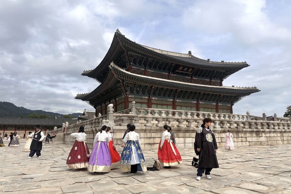 Mehrere Personen in traditionellen koreanischen Trachten stehen vor einem historischen Gebäude in Südkorea.