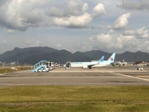 Zwei Flugzeuge auf dem Flughafen, eines mit der Aufschrift 'Jin Air' und das andere mit der Aufschrift 'Korean Air'.