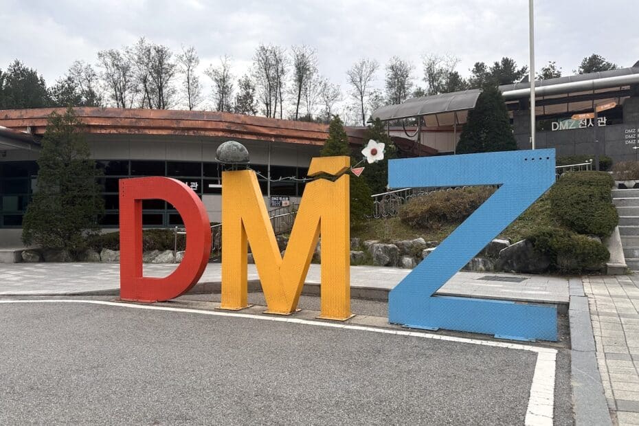 Bunte Skulptur mit den Buchstaben D, M und Z in rot, gelb und blau vor einem Gebäude im Freien.