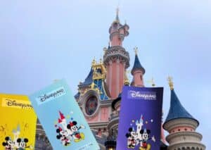 Drei Eintrittskarten für Disneyland Paris vor dem Schloss von Disneyland Paris.
