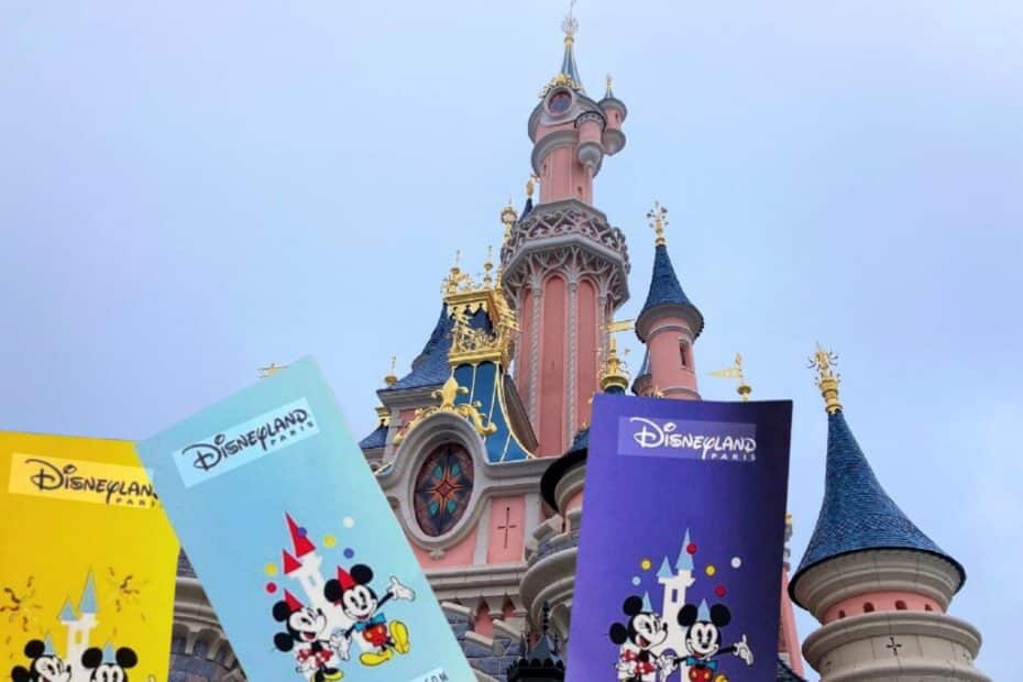 Drei Eintrittskarten für Disneyland Paris vor dem Schloss von Disneyland Paris.