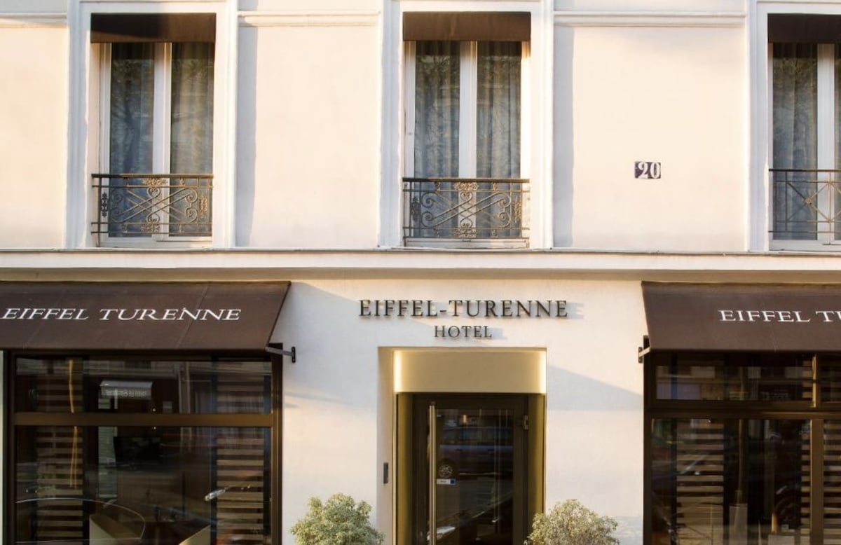 Fassade des Hotels Eiffel Turenne mit dem Namen des Hotels über dem Eingang und Fenstern mit Vorhängen. - Paris familienfreundliches Hotel