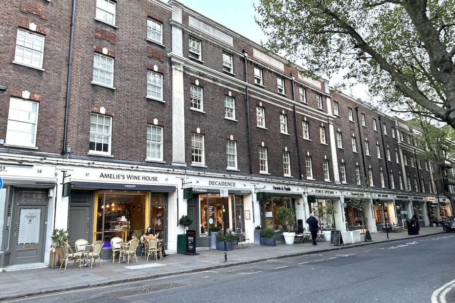 Mehrstöckiges Gebäude mit mehreren Geschäften und einem Café in einer städtischen Umgebung.