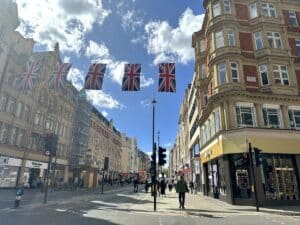Straße mit mehreren britischen Flaggen, die über die Straße hängen, und Gebäuden im Hintergrund.