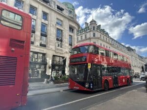 Roter Doppeldeckerbus der Linie 12 fährt auf einer Straße in London mit historischen Gebäuden im Hintergrund.
