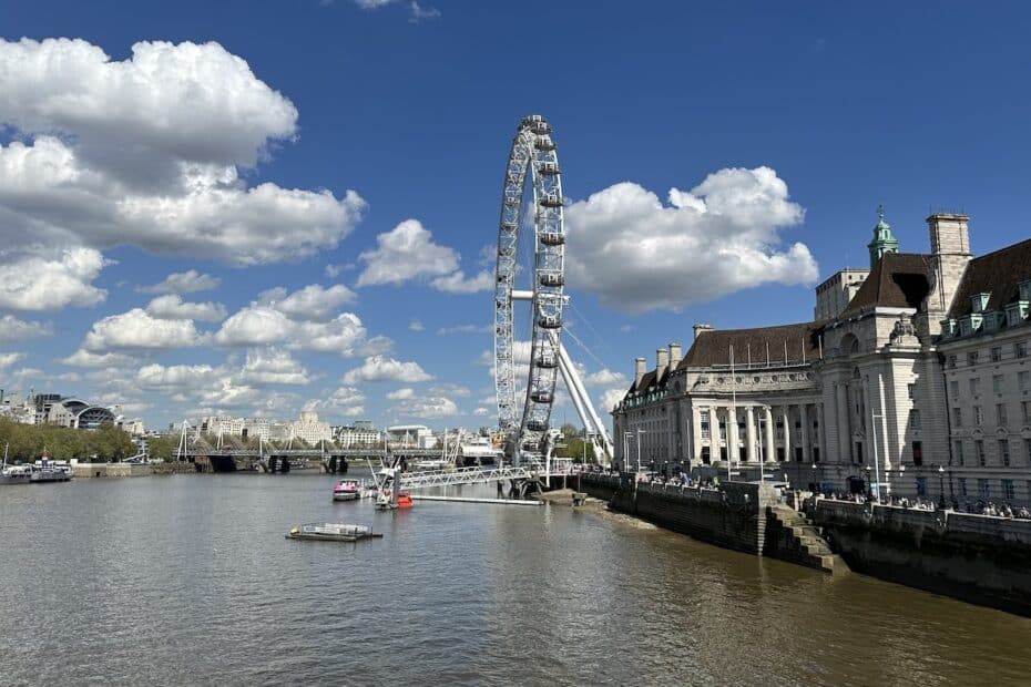 London Eye, ein großes Riesenrad am Südufer der Themse, umgeben von Wolken und blauen Himmel.