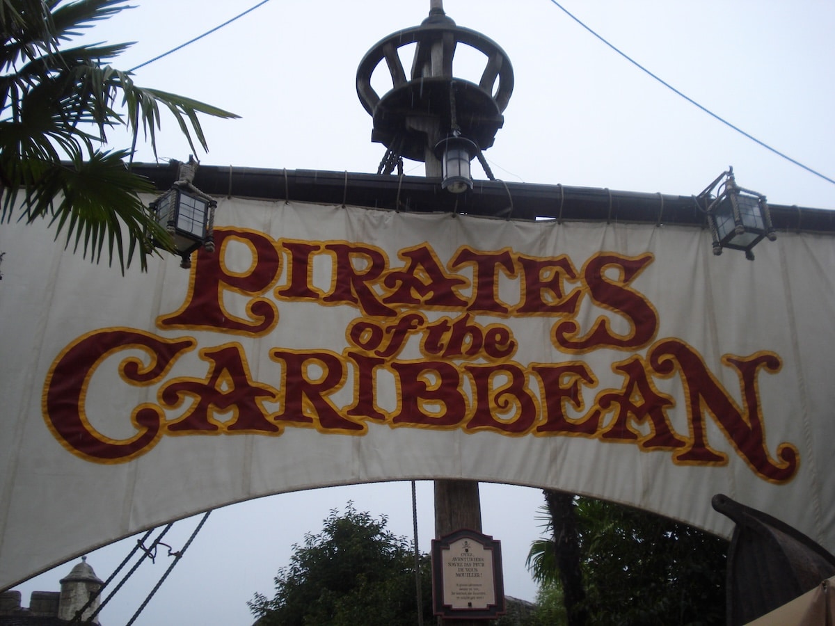 Banner mit der Aufschrift 'Pirates of the Caribbean' in rot-gelber Schrift auf einem weißen Hintergrund.