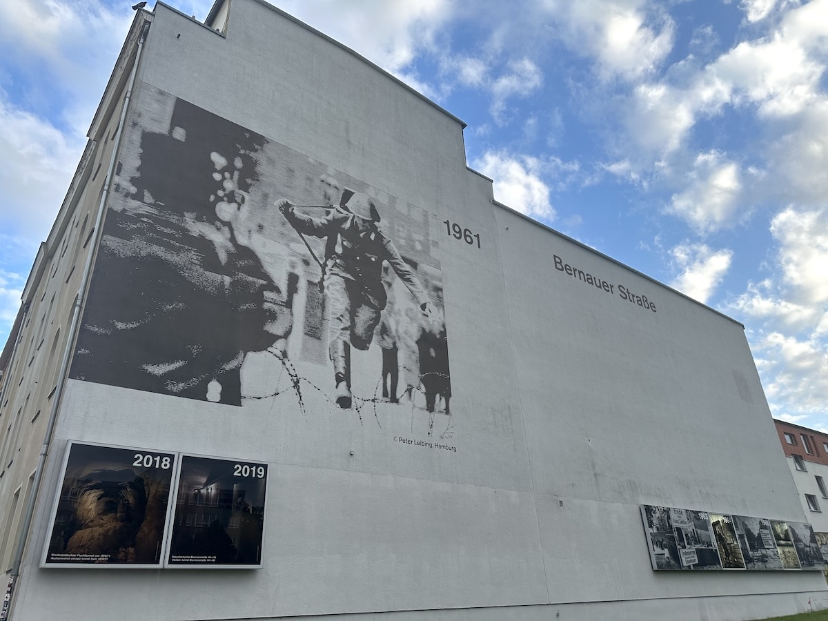 Wandgemälde auf einem Gebäude in der Bernauer Straße mit historischen Bildern und dem Jahr 1961.