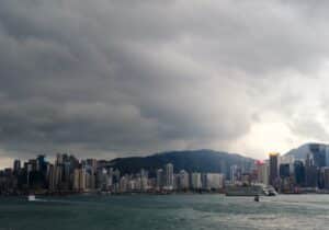 Blick auf die Skyline von Hongkong mit Wolken und Bergen im Hintergrund.