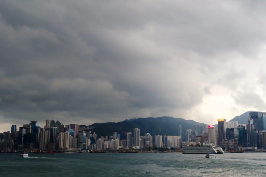 Blick auf die Skyline von Hongkong mit Wolken und Bergen im Hintergrund.