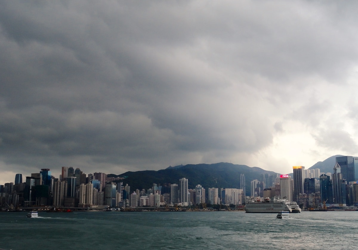 Blick auf die Skyline von Hongkong mit Wolken und Bergen im Hintergrund.