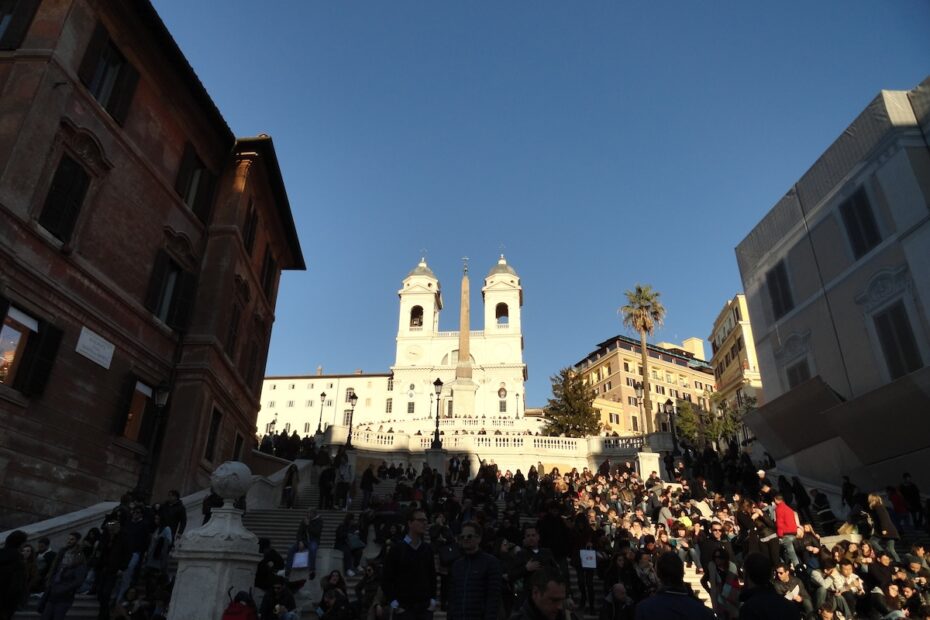 Rom: Spanische Treppe mit Obelisk, große Menge vor historischen Gebäuden, blauer Himmel, ikonische Architektur rund um die Stadt