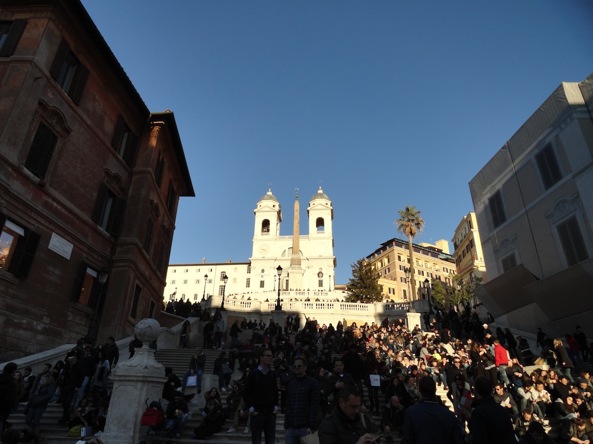 Rom: Spanische Treppe mit Obelisk, große Menge vor historischen Gebäuden, blauer Himmel, ikonische Architektur rund um die Stadt