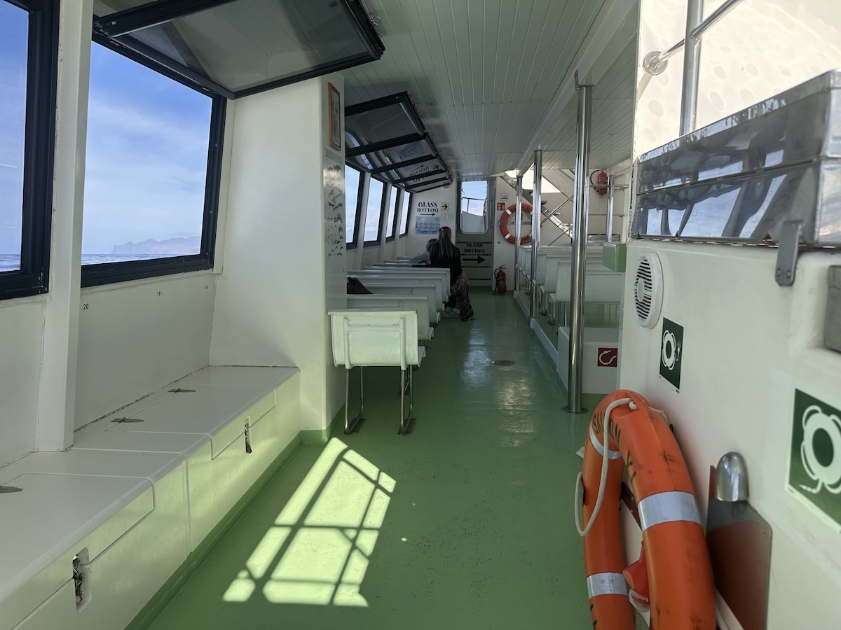Innenraum eines Bootes auf Gran Canaria mit grünem Boden, orangefarbenen Rettungsringen und Sitzbänken; Meer durch Fenster sichtbar; Startpunkt der Wal- und Delfinbeobachtung in Puerto Rico