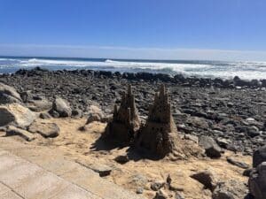 Sandfiguren am felsigen Strand vor Gran Canaria, blauer Ozean und klarer Himmel; Dünen- und Strandkulisse nahe Maspalomas, Inseltypische Küstenlandschaft