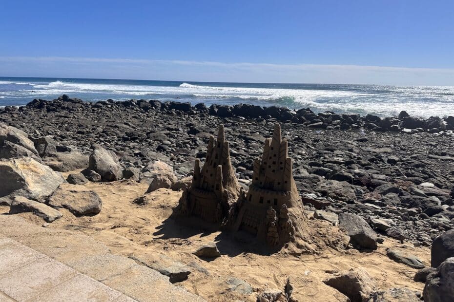 Sandfiguren am felsigen Strand vor Gran Canaria, blauer Ozean und klarer Himmel; Dünen- und Strandkulisse nahe Maspalomas, Inseltypische Küstenlandschaft