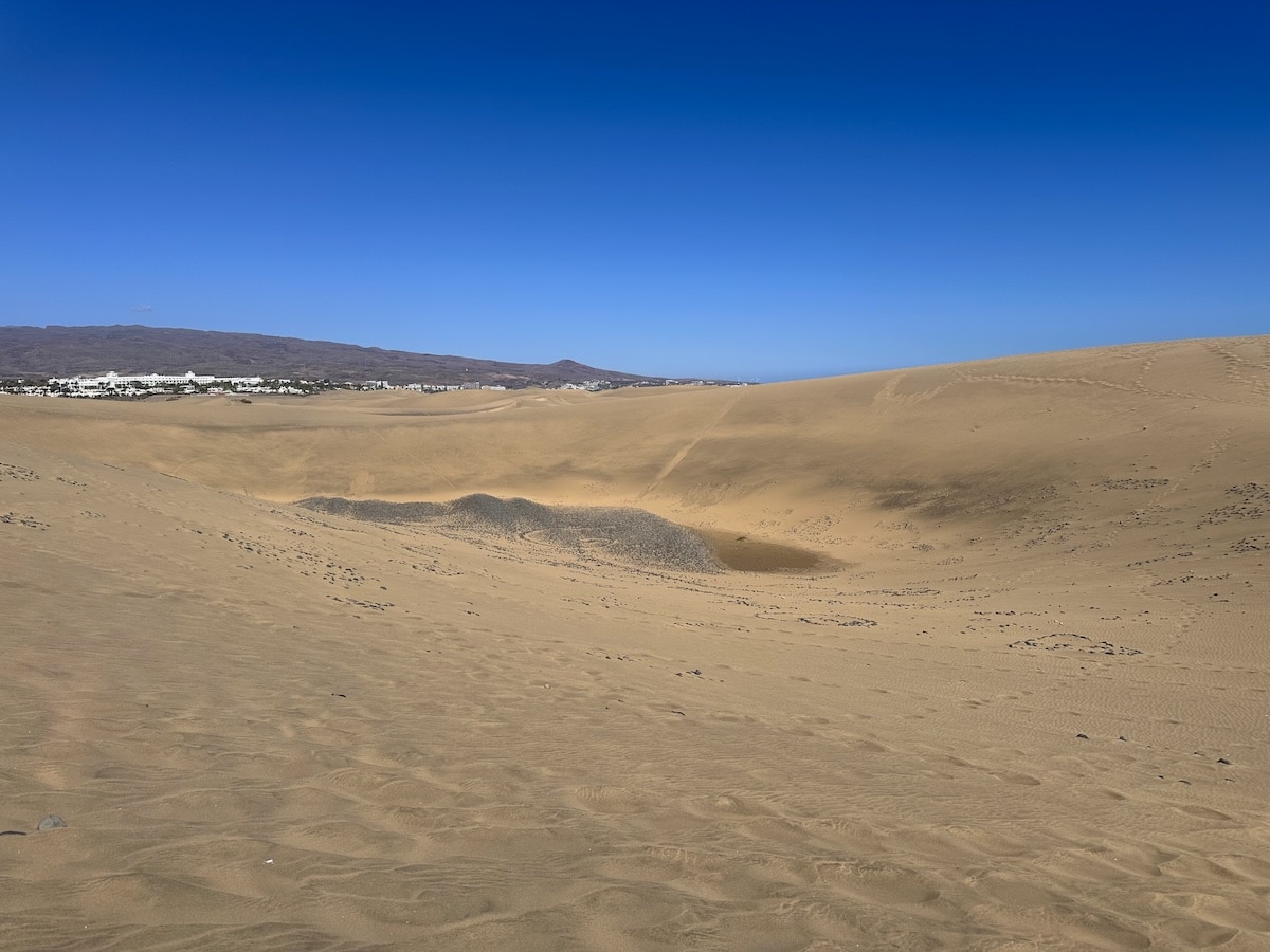 Sanddünen von Maspalomas auf Gran Canaria unter klarem blauem Himmel, weite Dünenlandschaft nahe der Küste mit Blick auf Playa del Inglés und Umgebung