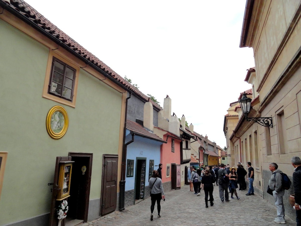 Pastellfarbene Häuser und Kopfsteinpflaster in einer schmalen Gasse beim Goldenes Gässchen der Prager Burg in Prag, mit Blick durch den Innenhof.
