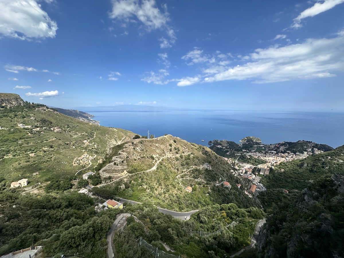 Von Taormina bis Isola Bella: türkisblaues Meer vor grünen Hügeln, kurvige Straßen und ein Panorama über Küste und kleine Orte bei blauem Himmel.