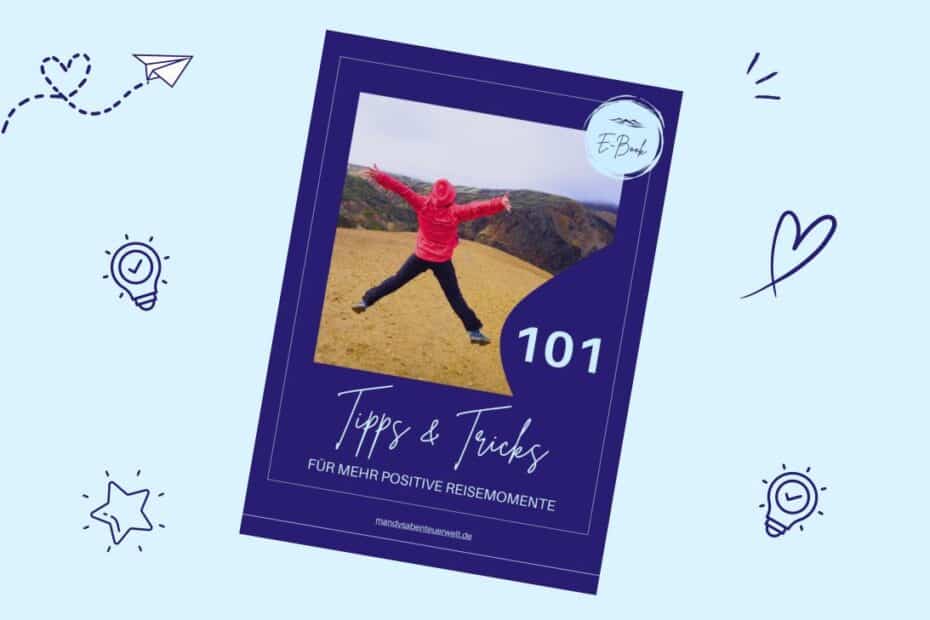Dunkelblaues Cover mit einer springenden Person vor Berglandschaft und dem Titel „101 Tipps & Tricks“ für positive Reiseerlebnisse.