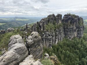 Von der Schrammsteinaussicht öffnet sich ein weiter Blick über markante Sandsteinfelsen, dichte Wälder und die sanfte Landschaft der Sächsischen Schweiz.