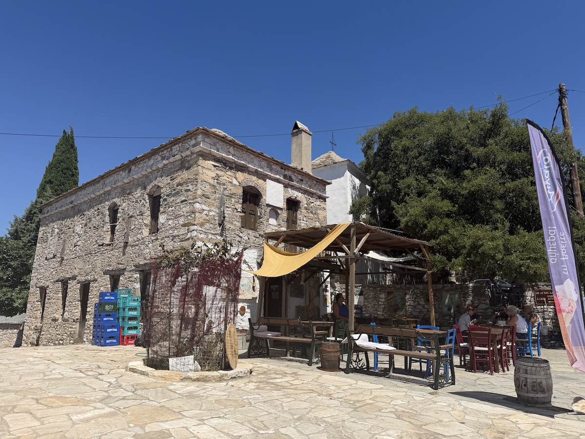 Historischer Steinhof mit steinernem Gebäude, Taverne, Sitzplätzen und Sonnensegel unter mediterranen Bäumen - Kastro bei einer Jeep Tour auf Thassos