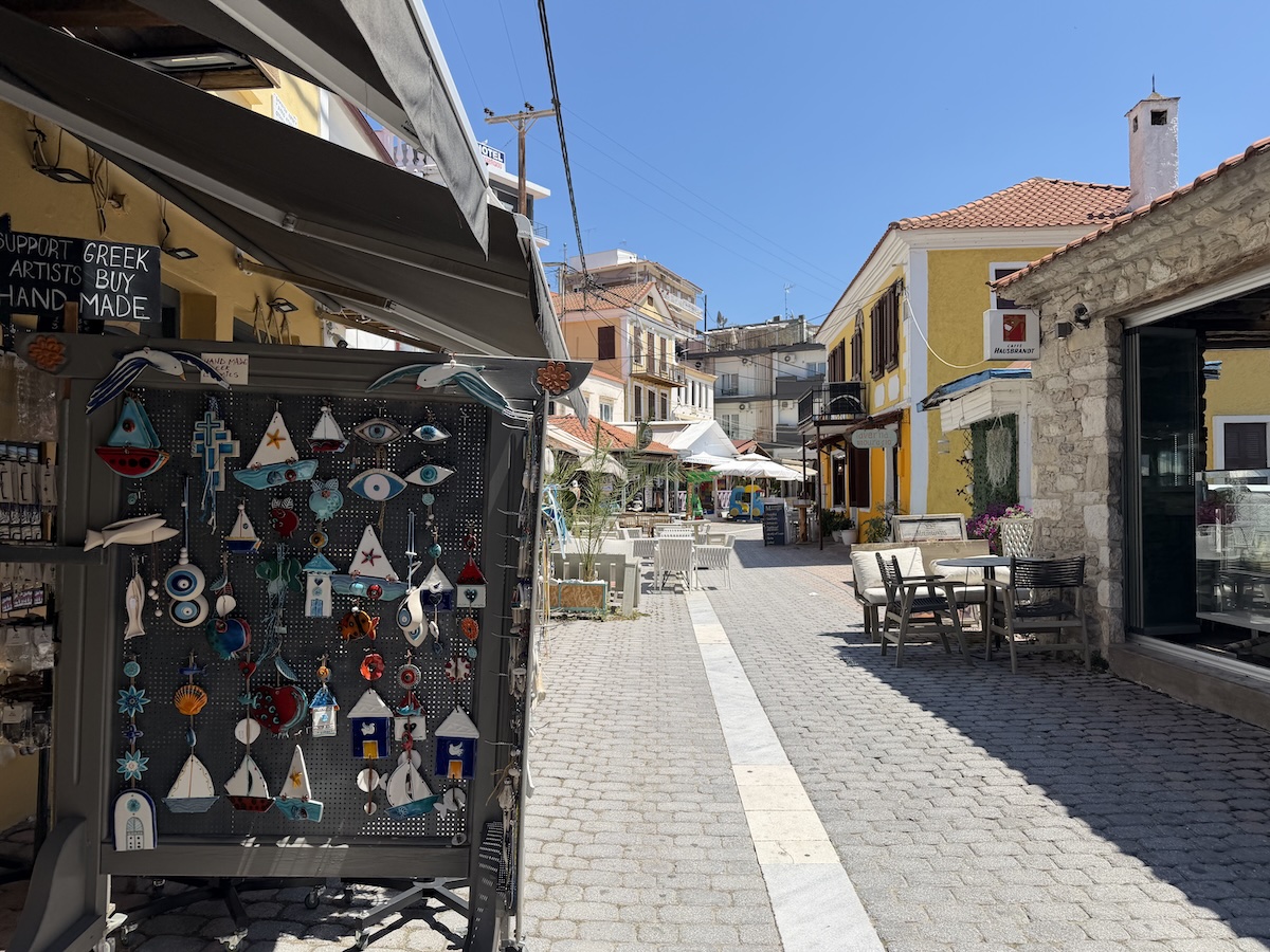 Helle Gasse in Limenaria auf Thassos mit Souvenirladen, Cafés, Natursteinfassade und blauem Himmel