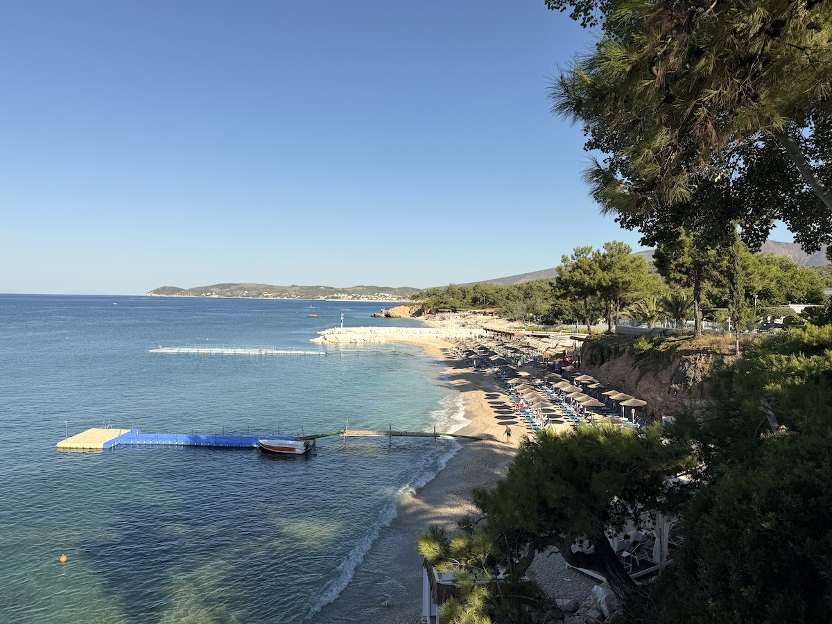 Kristallklares blaues Meer vor einer ruhigen Küste bei Pefkari nahe Potos auf Thassos mit kleinem Strand und Bootssteg