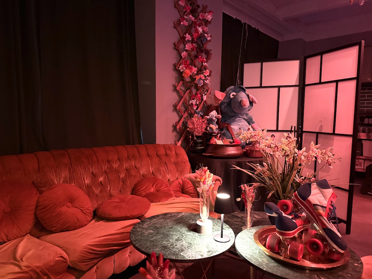 Festlich rot beleuchteter Dinnerbereich von Movie2Menu Berlin mit Samtsofa, gedeckten Tischen und Ratatouille-Dekoration