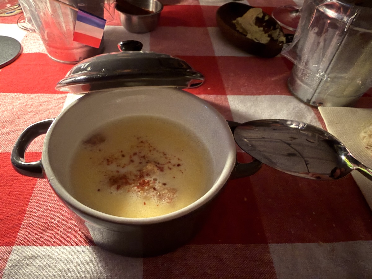 Cremige Suppe im kleinen Topf auf rot-weiß karierter Tischdecke beim Ratatouille-Abend