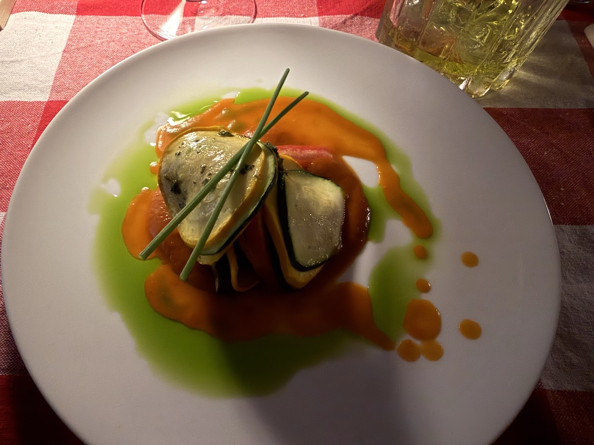 Angerichtetes Gemüsegericht mit Zucchini, Schnittlauch und grüner sowie orangefarbener Sauce beim Ratatouille-Abend