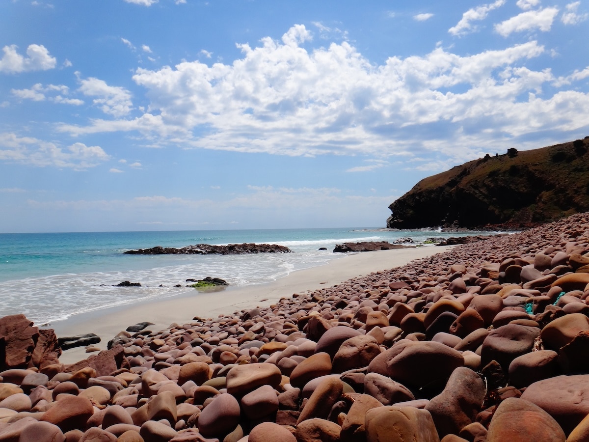 Türkisblaues Meer trifft an Stokes Bay auf Kangaroo Island auf einen breiten Strand mit runden roten Felsen.