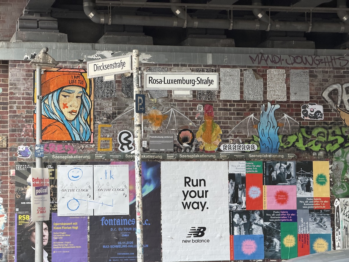 Bunte Streetart mit Porträt, Plakaten und Wegweisern in der Rosa-Luxemburg-Straße in Berlin-Mitte