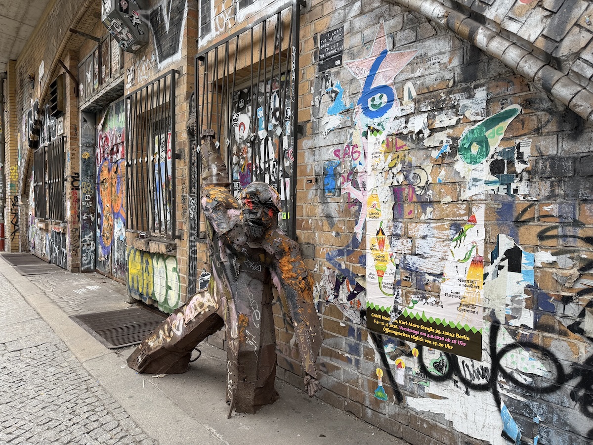 Bunte Streetart mit Paste-ups, Graffiti und einer Metallskulptur an einer Berliner Hauswand im urbanen Hinterhof