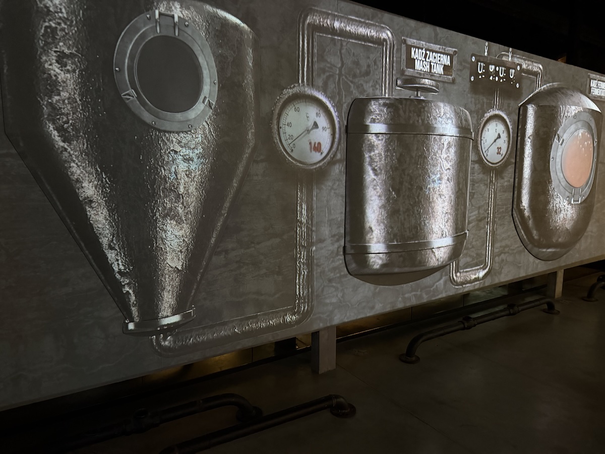 Industrielle Maschinenwand mit dem gut lesbaren Hinweis „Mash Tank“, Manometern, Rohrleitungen und Bullaugen.